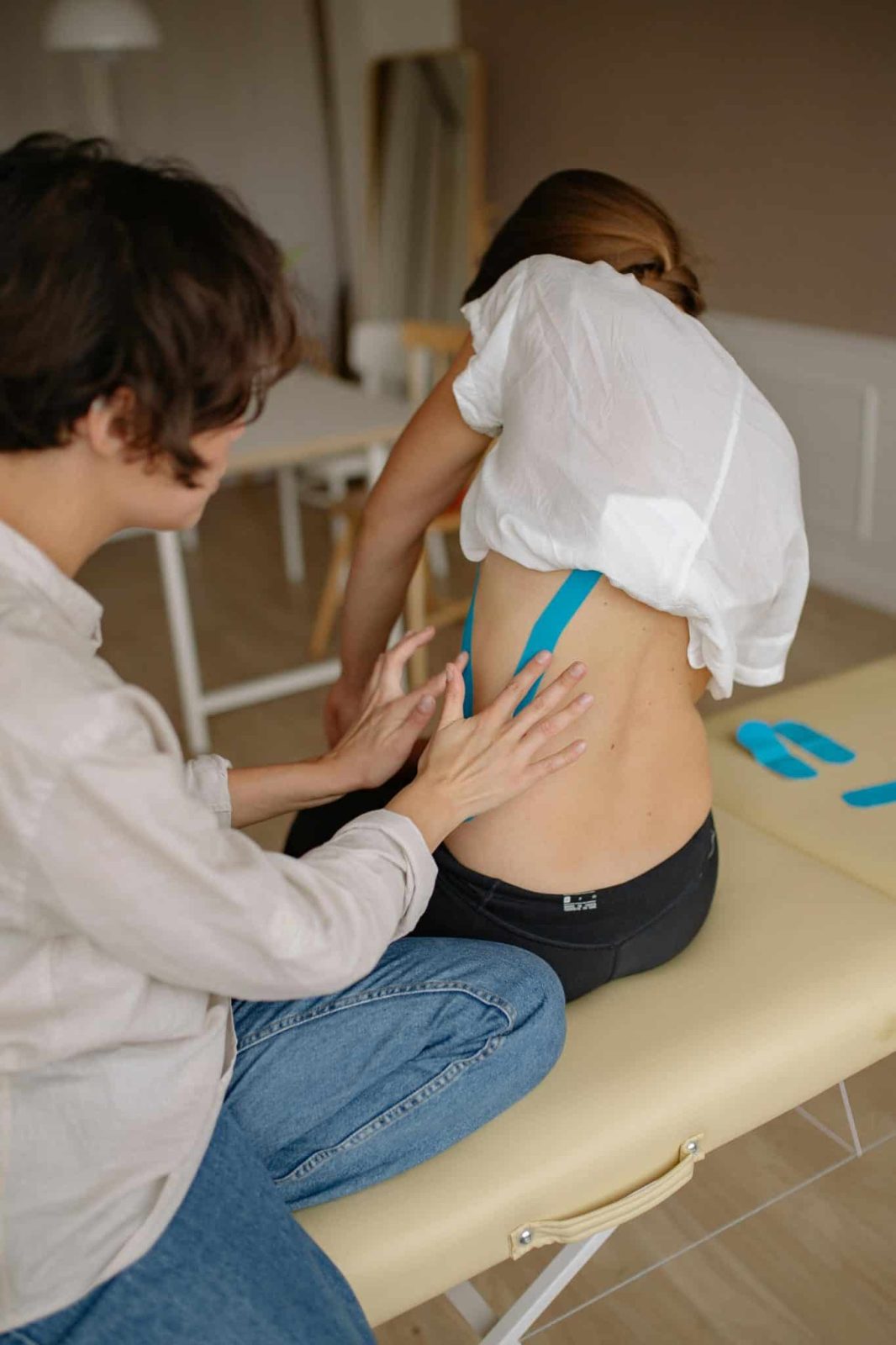 kinesiologist putting kinesio tape on woman's body