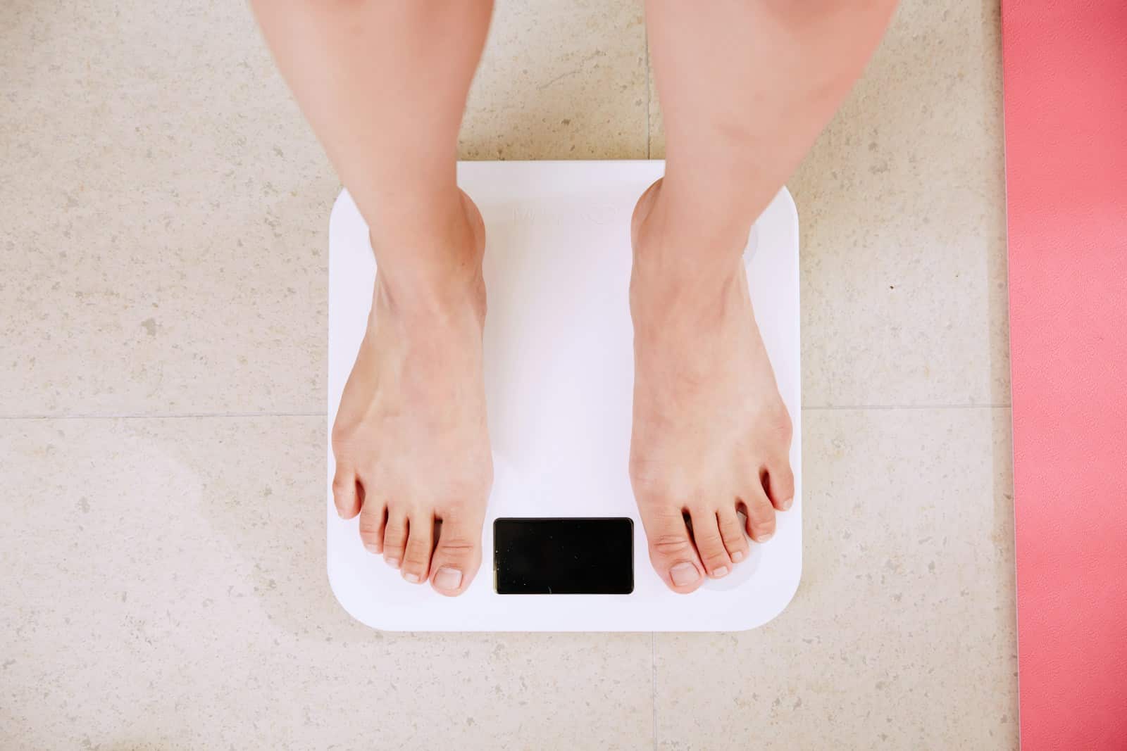 person standing on white digital bathroom scale. Dietician to help you eat better and lose weight naturally