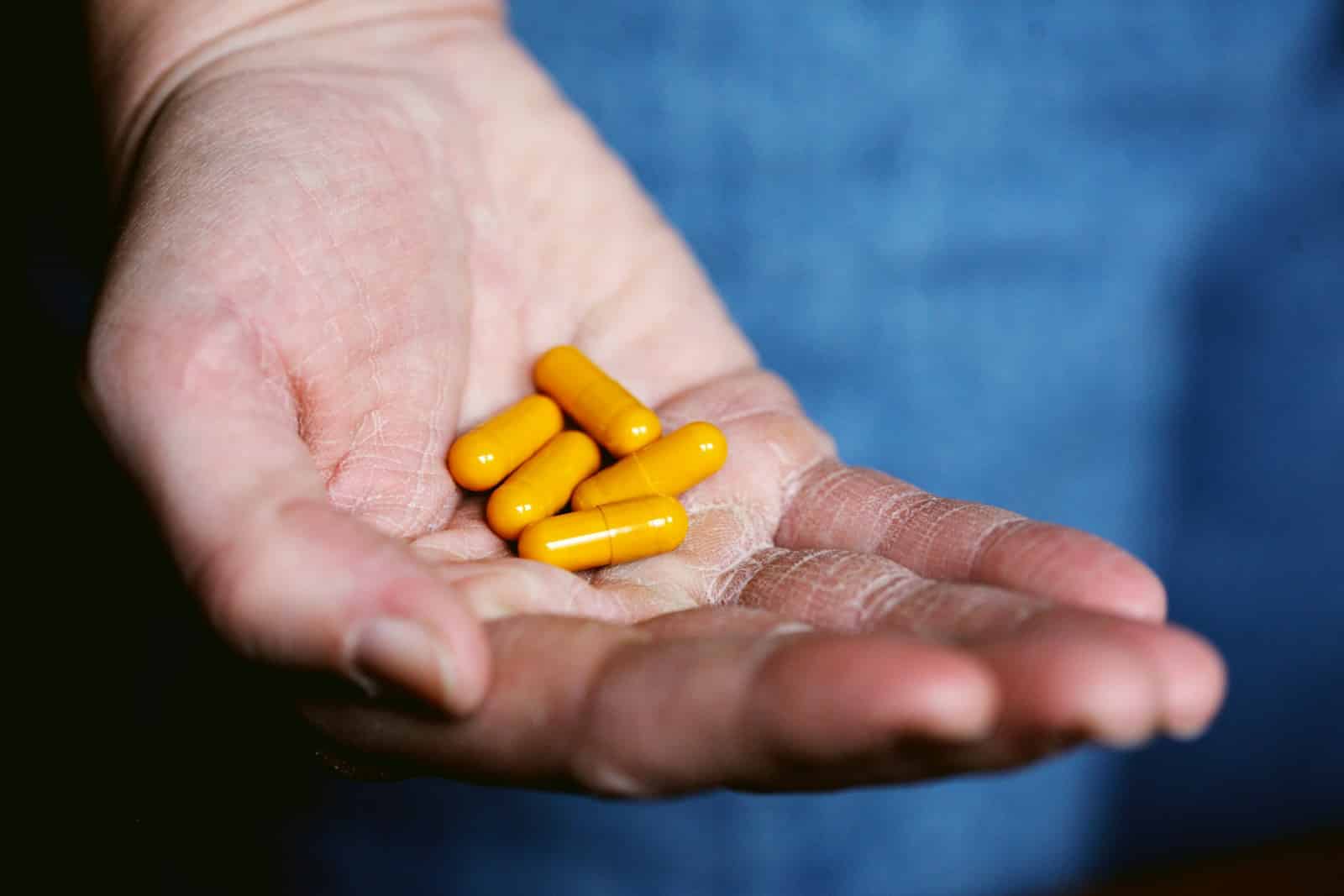 yellow medication pill on persons hand. Weight Loss Aids.