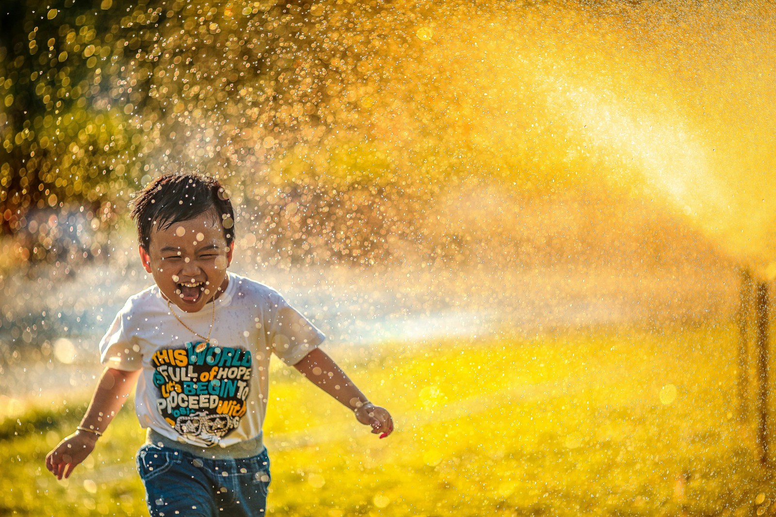 a young boy running through a sprinkler. Paediatric Physio near me in Wavell Heights