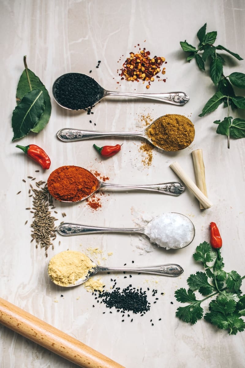 five gray spoons filled with assorted-color powders near chilli. Naturopaths